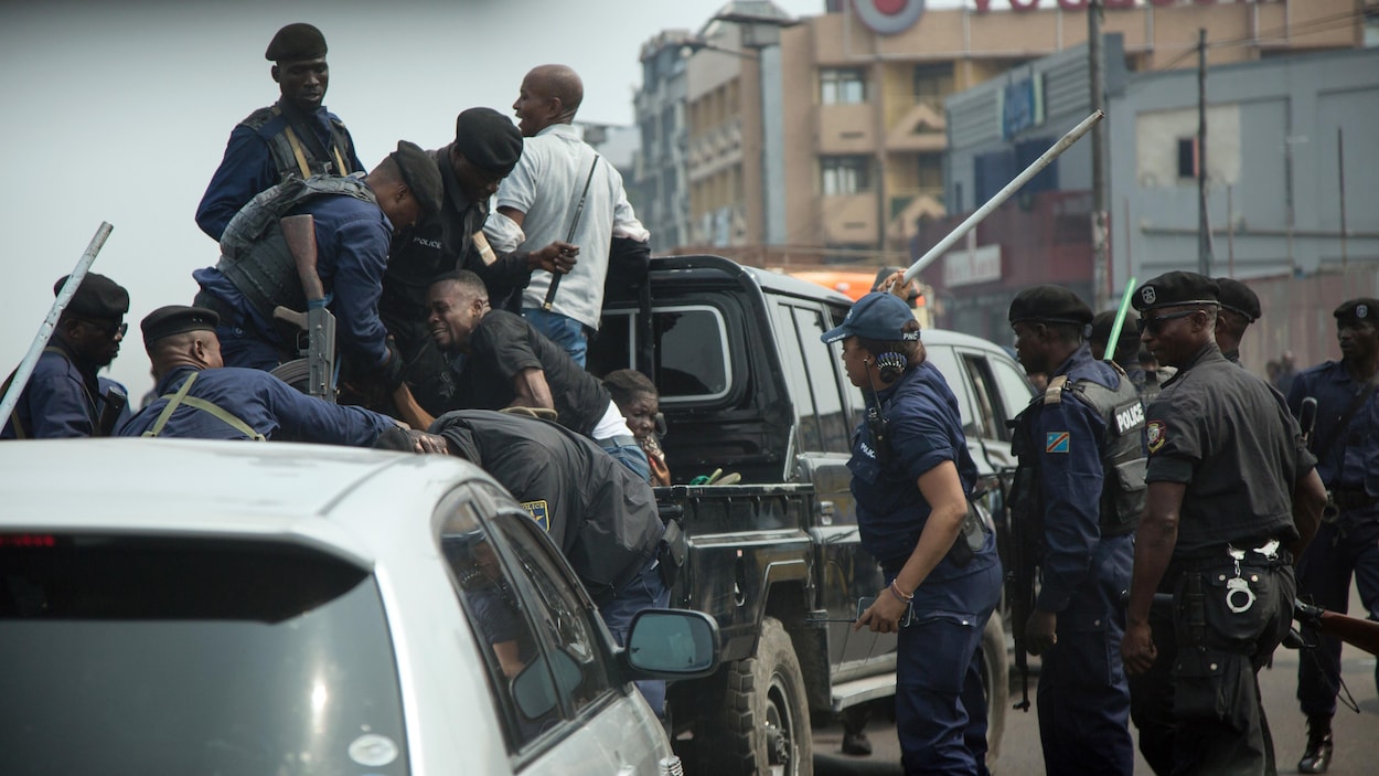 Un manifestant est tiré à l'arrière d'une camionnette de la police sous la menace de recevoir un coup de bâton.