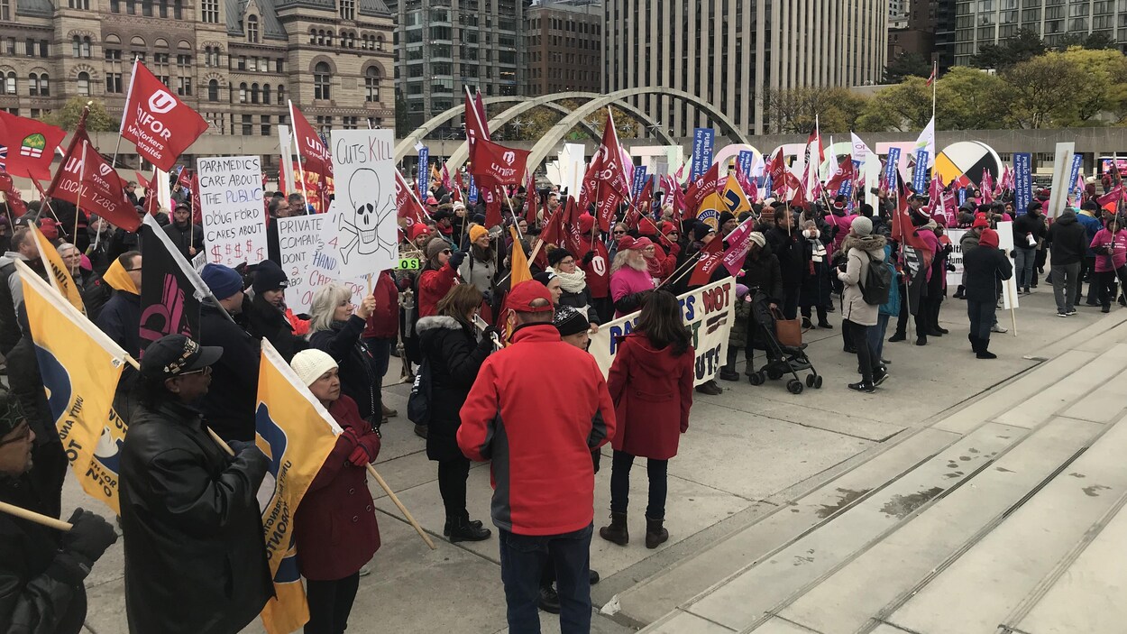 Des centaines de manifestations avec des t-shirts rouge sur une place du centre-ville de Toronto.