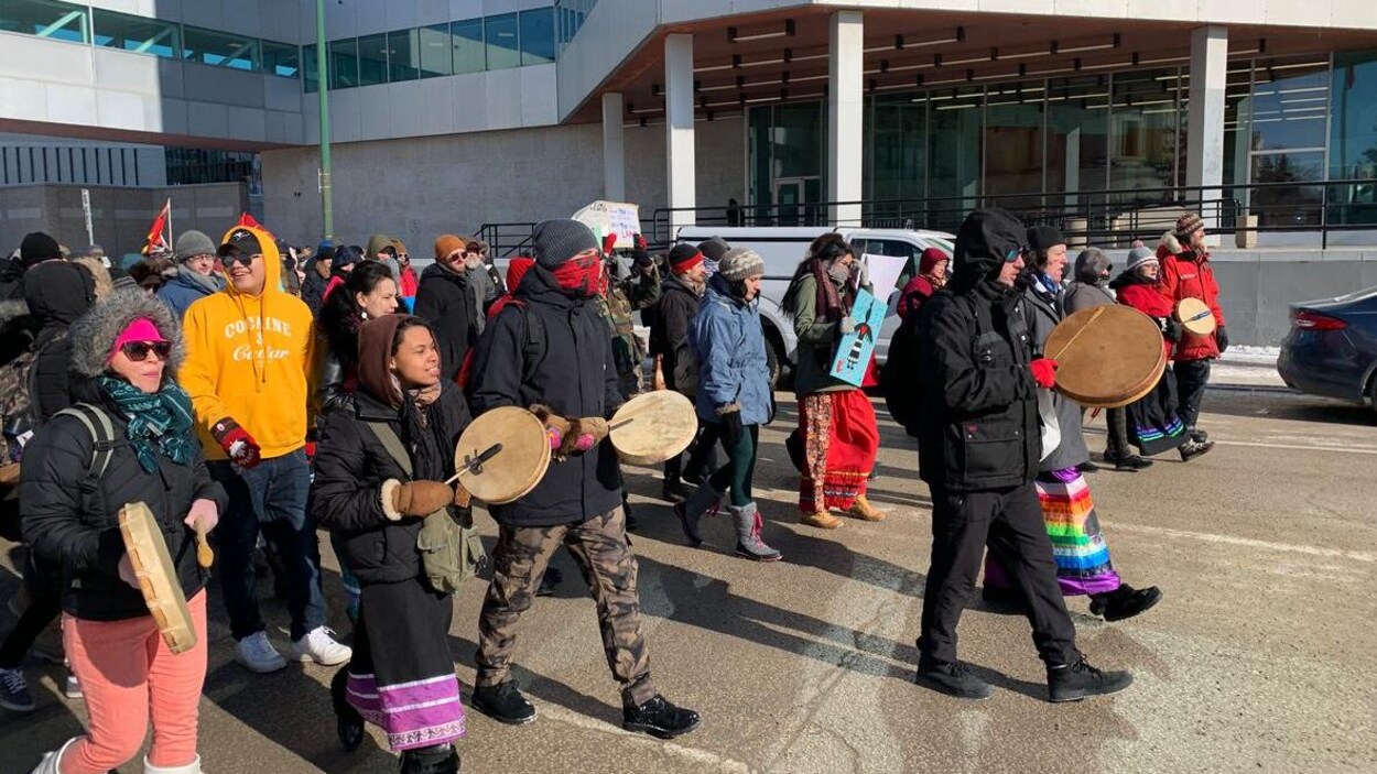 Des dizaines de personnes en habits d'hiver colorés marchent dans la rue.