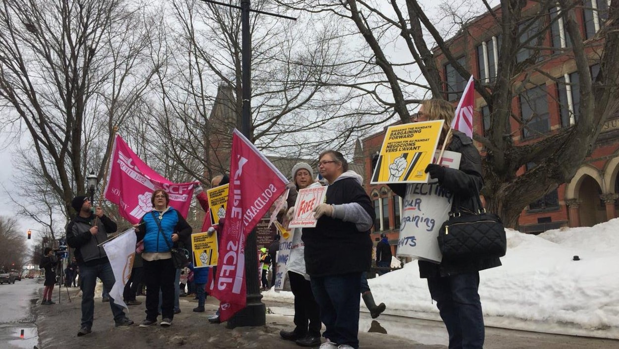 Des syndiqués qui brandissent pancartes et banderoles au centre-ville de Fredericton.