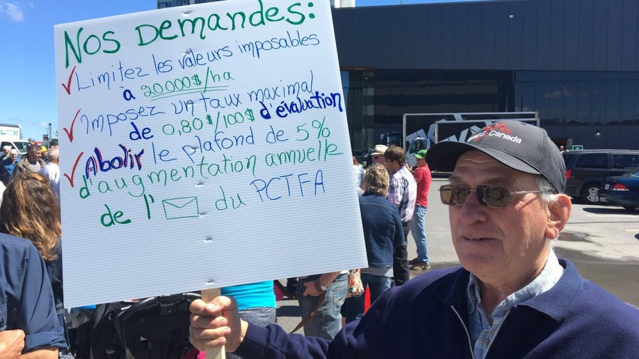 Un homme tient une pancarte énumérant quelques demandes.