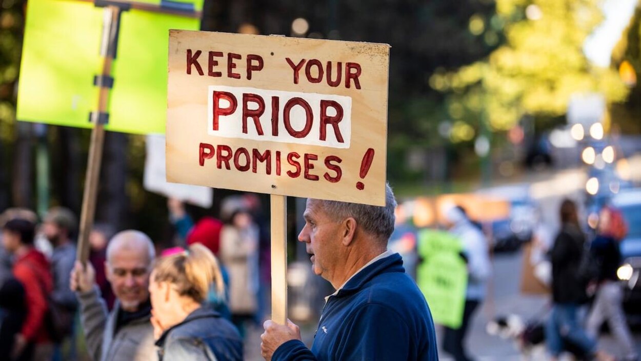 Des manifestants dans une rue de Vancouver, dont l'un porte une affiche qui indique : « Tenez vos promesses au sujet de Prior! »
