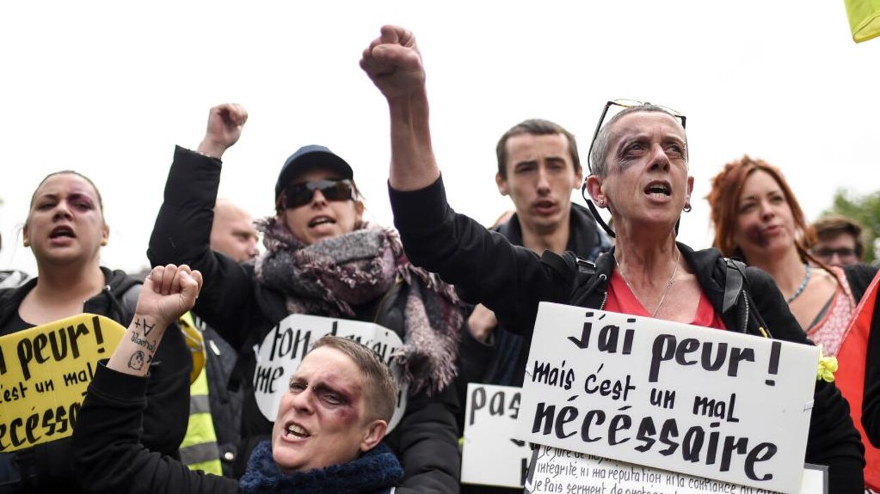 Des femmes manifestent, le poing levé, maquillées pour plusieurs d'un oeil au beurre noir.