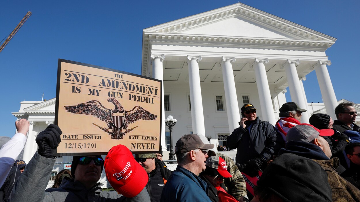 Le 20 janvier 2020, un militant proarmes tient une casquette appuyant Donald Trump et une pancarte disant « Le deuxième amendement est mon permis d'armes à feu ». Il se trouve devant le capitole de l'État de Virginie.