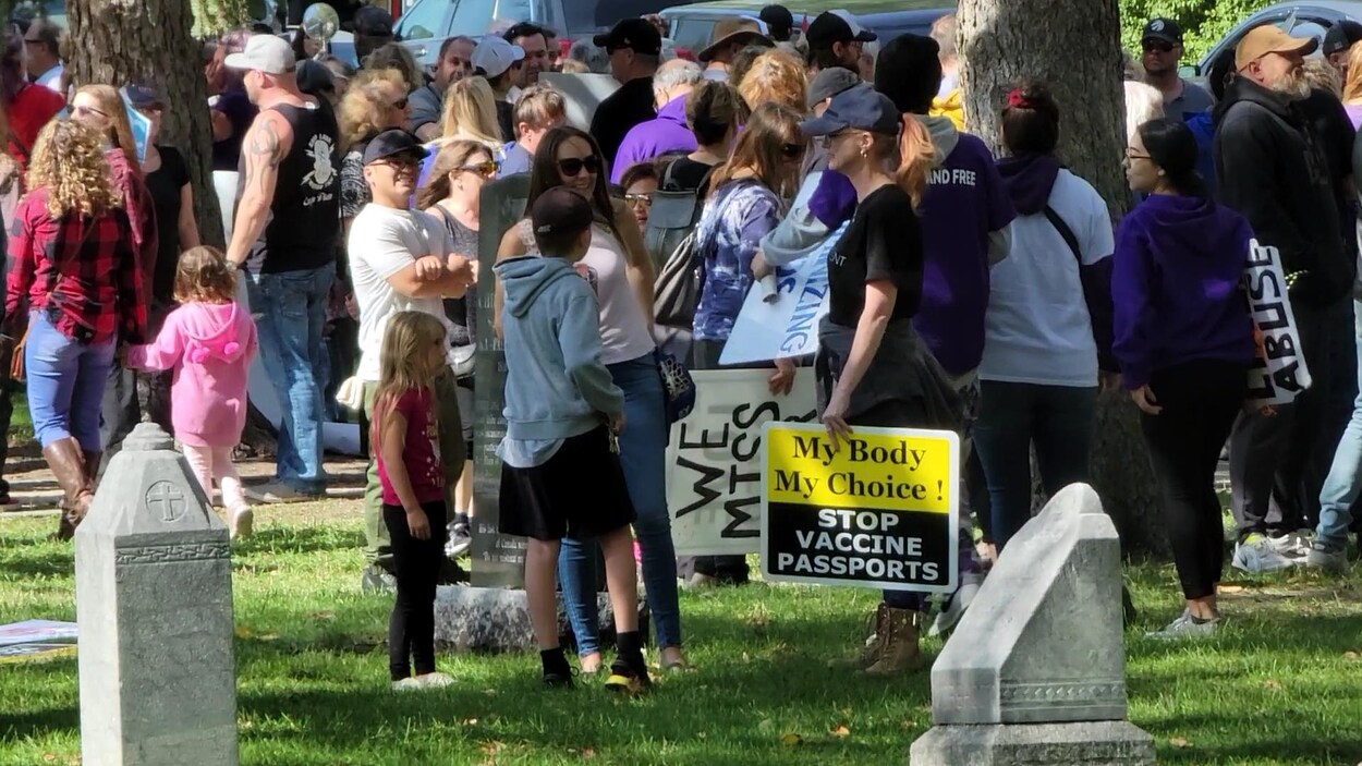 Des personnes sont rassemblées sur le terrain de la cathédrale de Saint-Boniface avec des affiches anti-vaccination.
