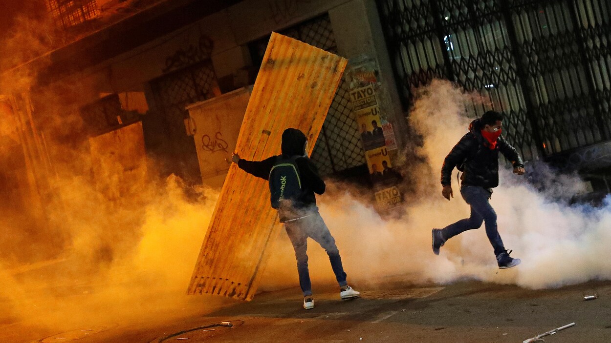 Deux manifestants au milieu de la fumée de gaz lacrymogènes.