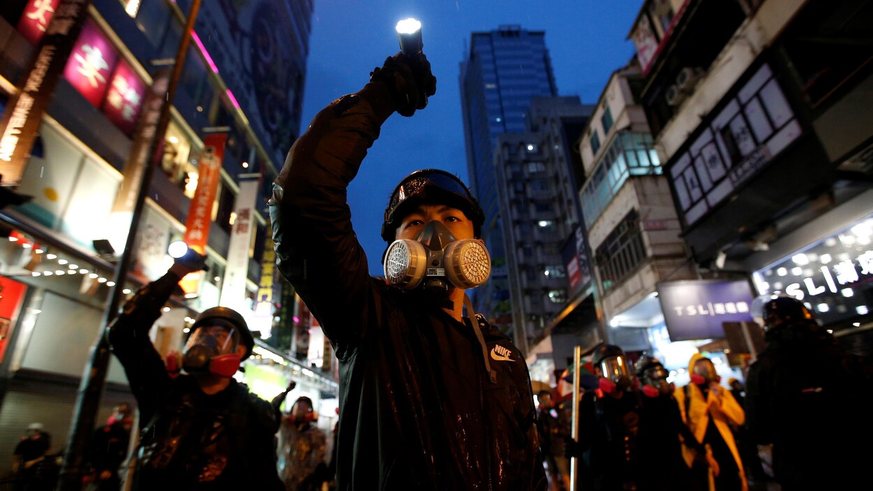 Des manifestants portant des masques et des lampes torches dans les rues de Hong Kong.