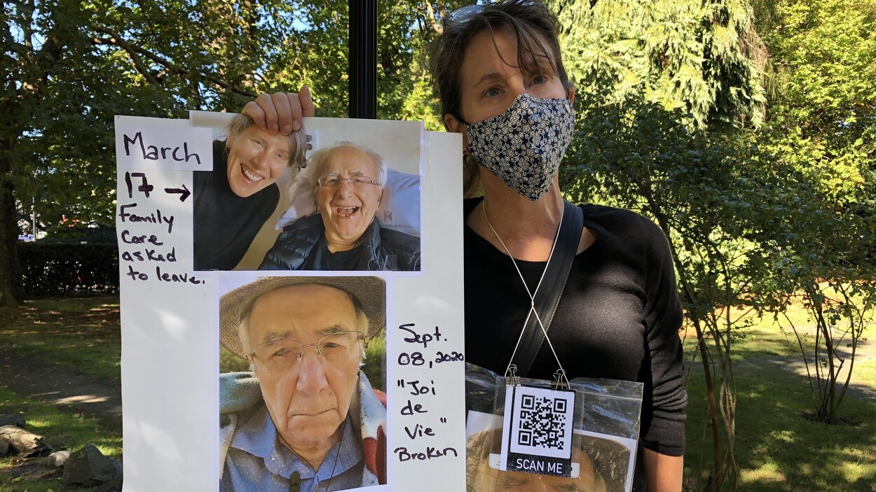 Hélène Michaud tenant dans ses mains une affiche avec des photos de son père.