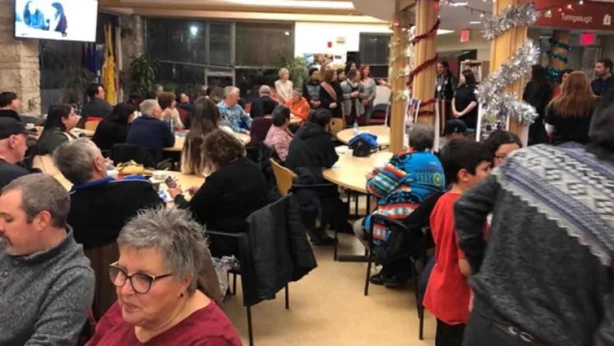 Un groupe de personnes dans une salle décorée autour de plusieurs tables.