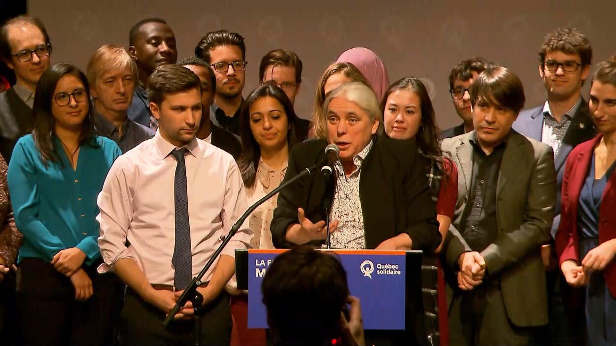 Manon Massé parle dans un micro, entourée de plusieurs délégués et de Gabriel Nadeau-Dubois.