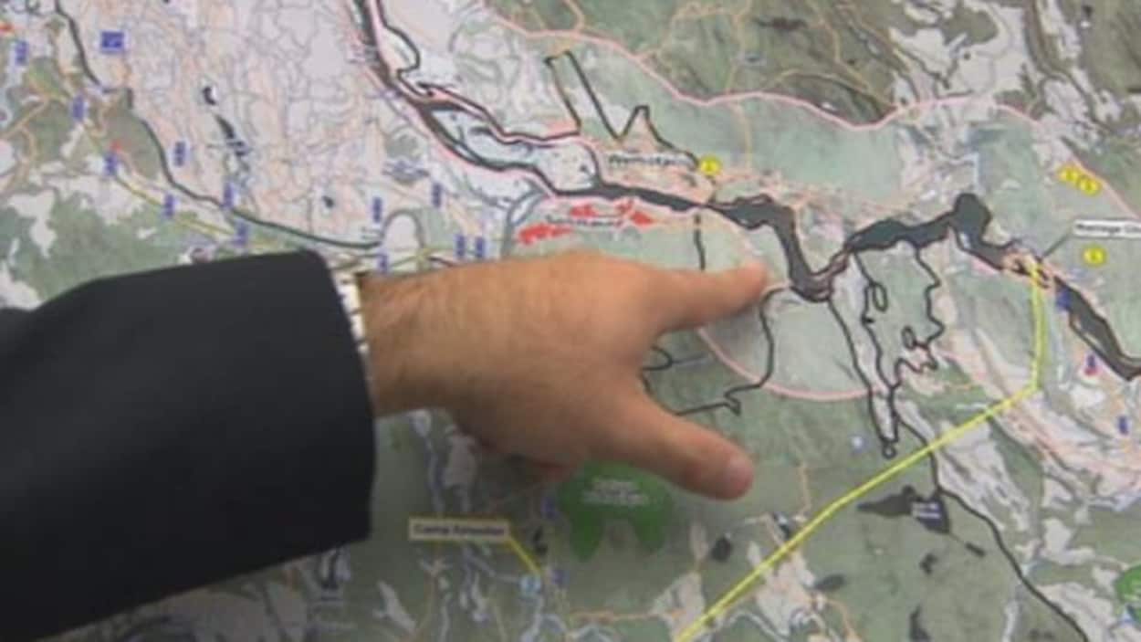 Une main pointe une rivière sur une carte.