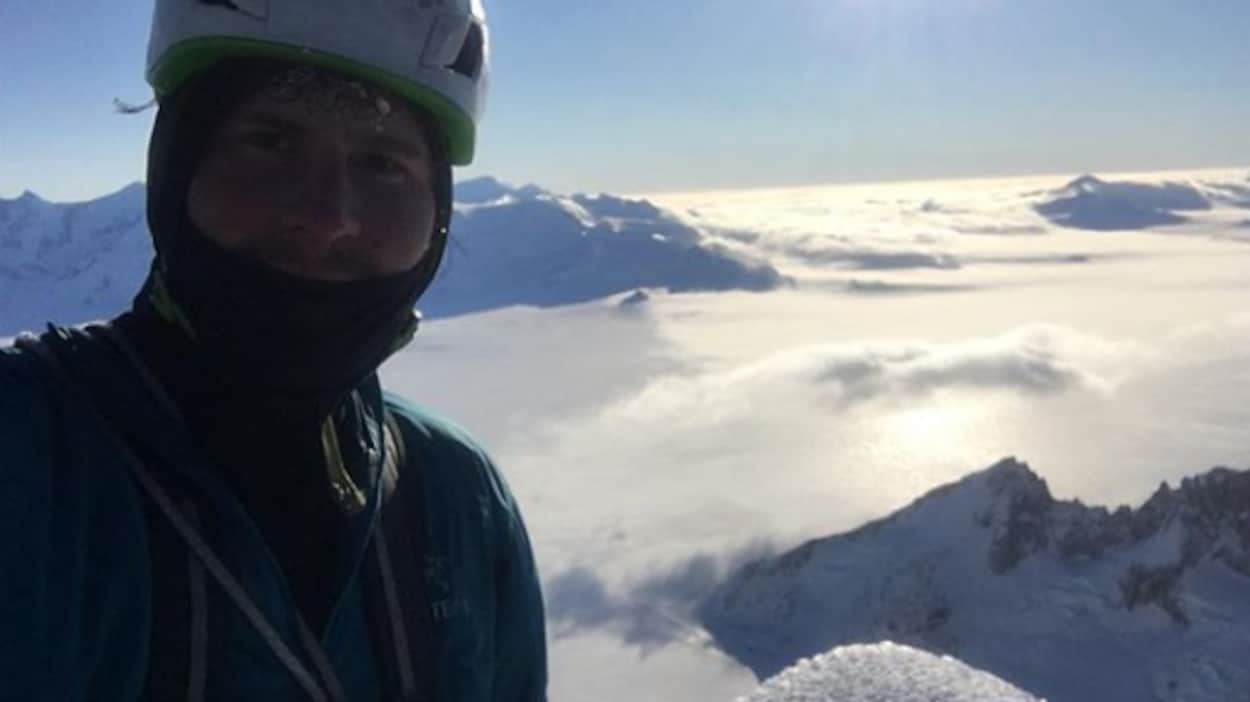 L'alpiniste Marc-André Leclerc au sommet d'une montagne portant un casque sous le soleil. L'alpiniste Marc-André Leclerc au sommet d'une montagne portant un casque sous le soleil.
