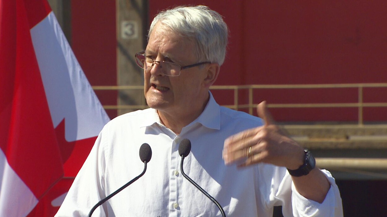 Marc Garneau en point de presse, devant le drapeau canadien, au port de Vancouver. Marc Garneau en point de presse, devant le drapeau canadien, au port de Vancouver.