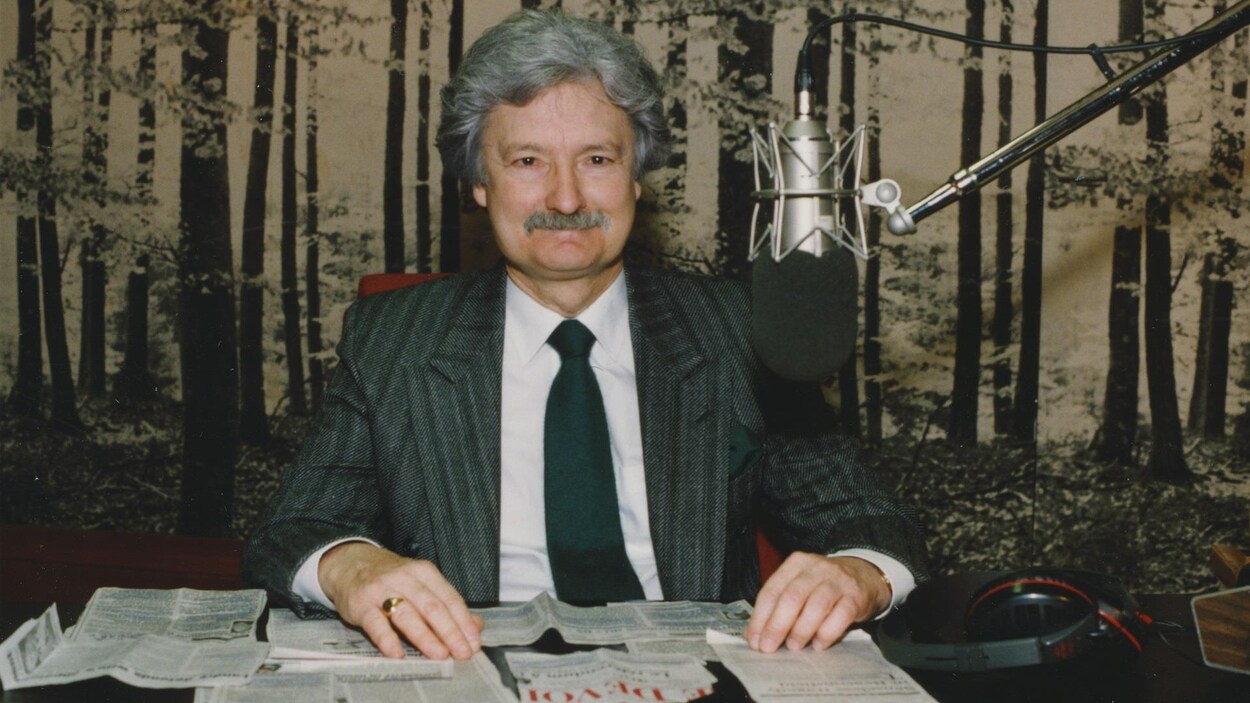 Marc Laurendeau, assis dans un studio radio avec des coupures de presse posées devant lui.