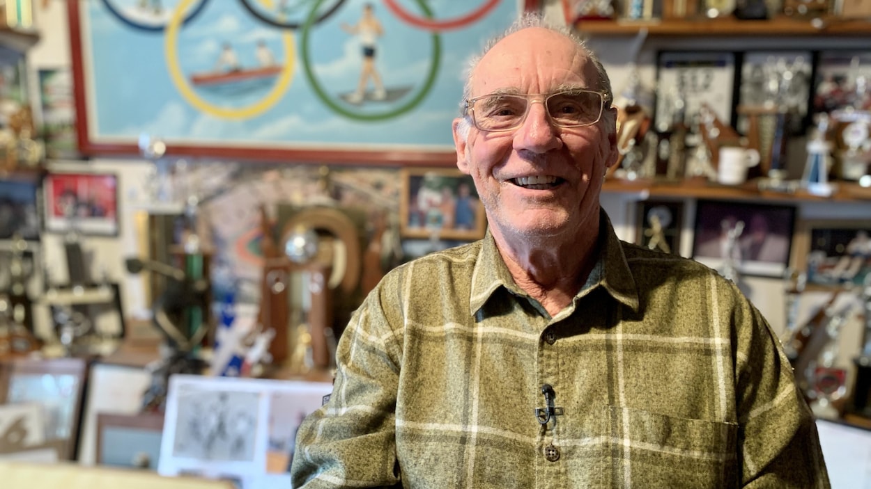 L'homme assis devant des souvenirs de prix qu'il a gagnés, par exemple, des trophées.
