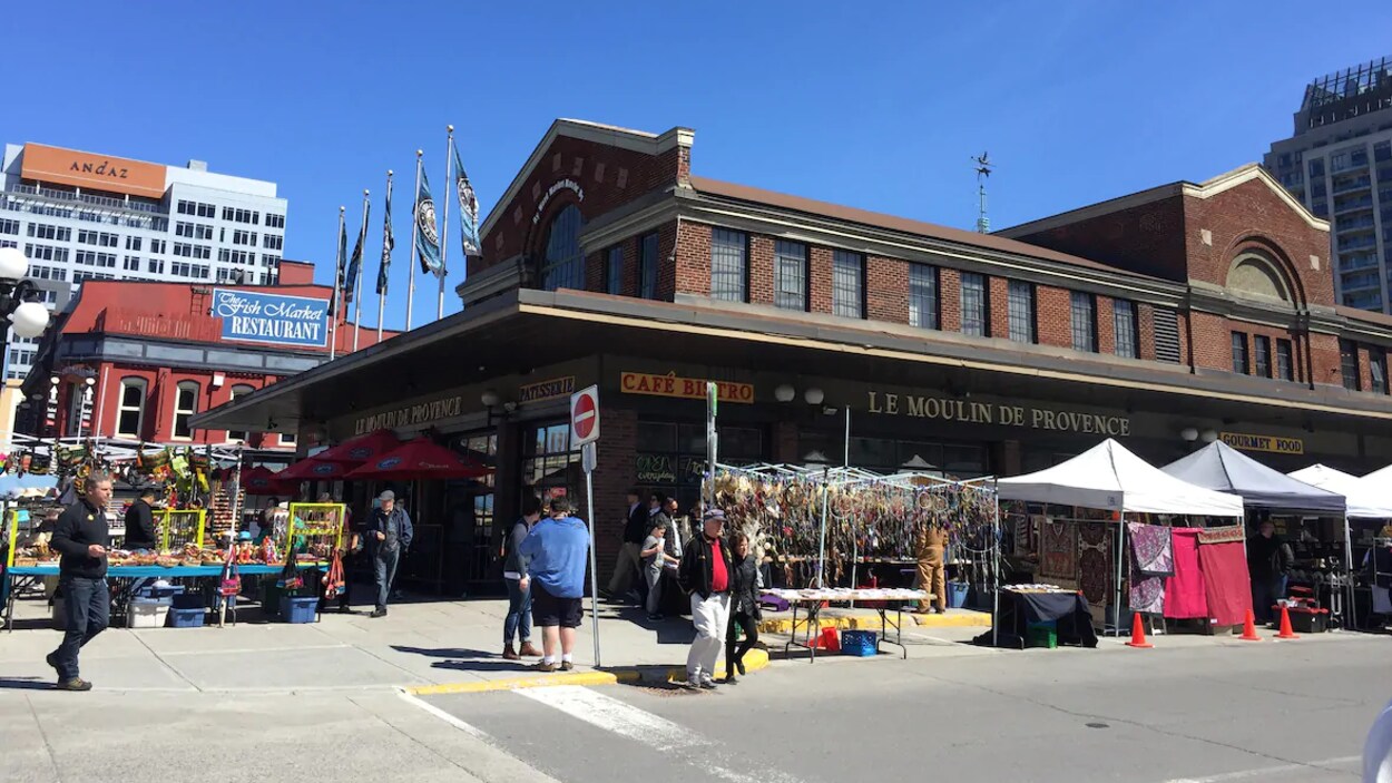 Des passants marchent le long des commerces du marché By.