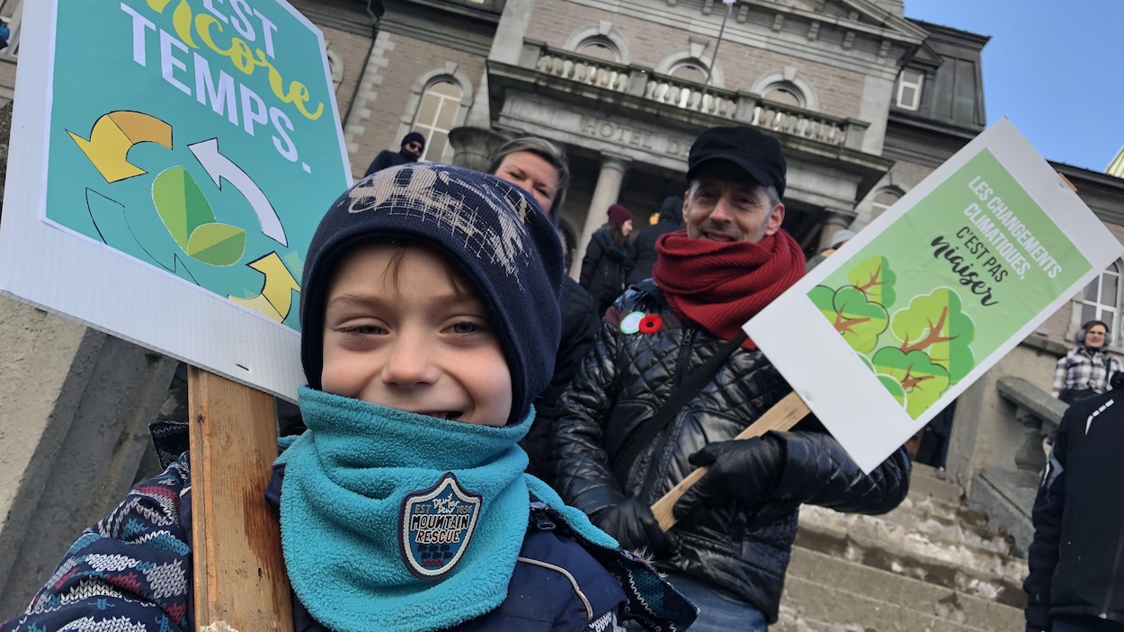Un enfant et un homme tiennent des pancartes.
