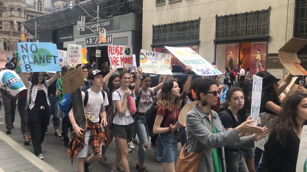 Des jeunes qui manifestent brandissant des pancartes.