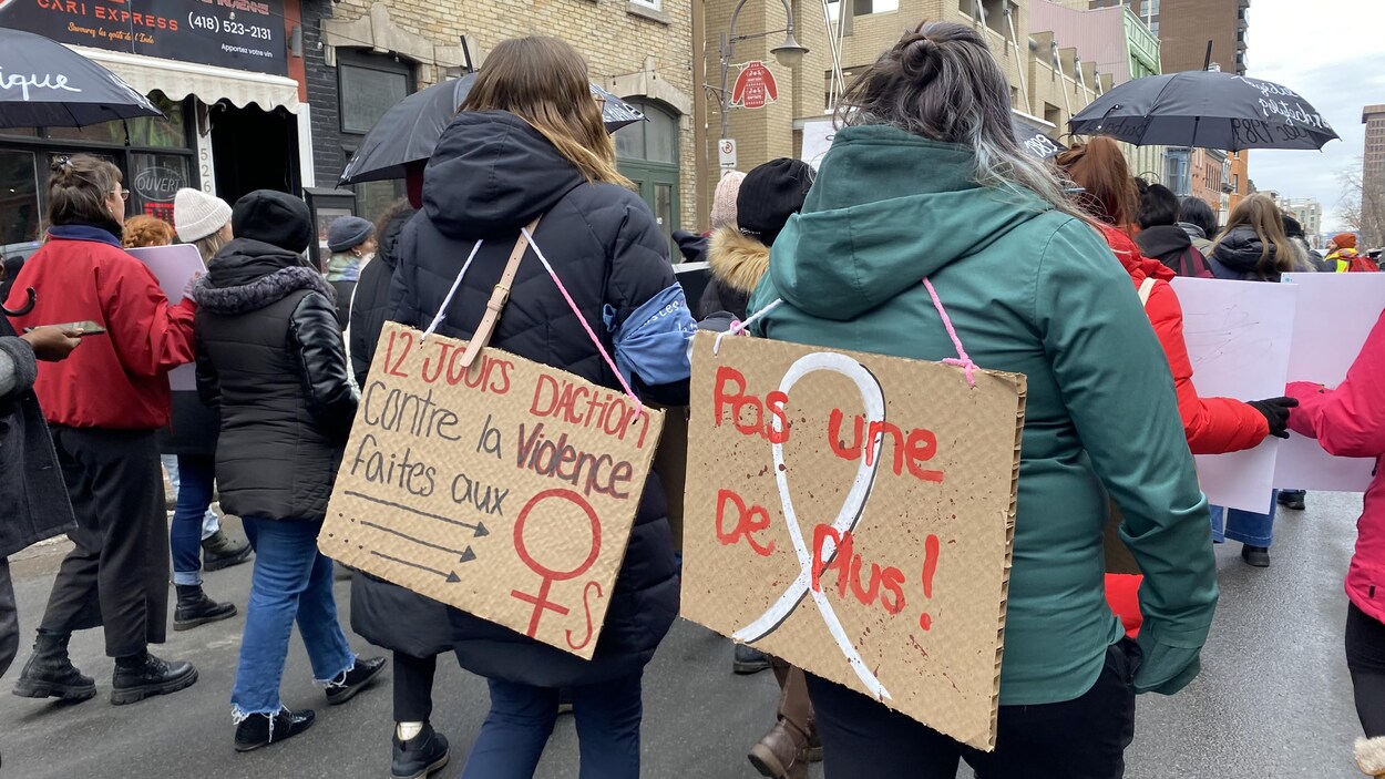 Des femmes marchent avec des pancartes dans le dos où l'on peut lire « 12 jours d'action contre la violence faite aux femmes » et « Pas une de plus! »