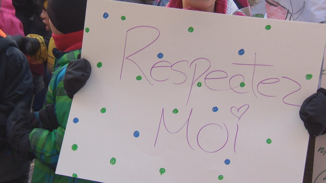 Un enfant tenant un affiche sur laquelle est écrit « Respectez-moi ». Un enfant tenant un affiche sur laquelle est écrit « Respectez-moi ».