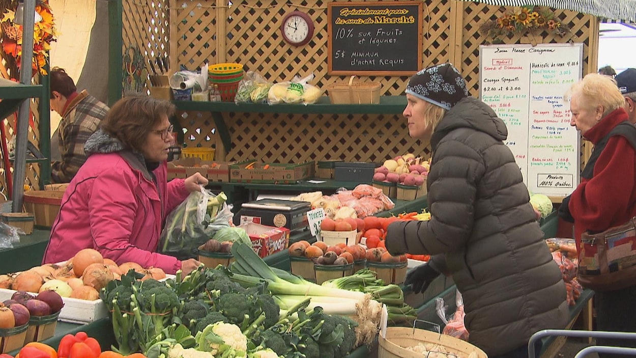 Une femme achète des légumes.