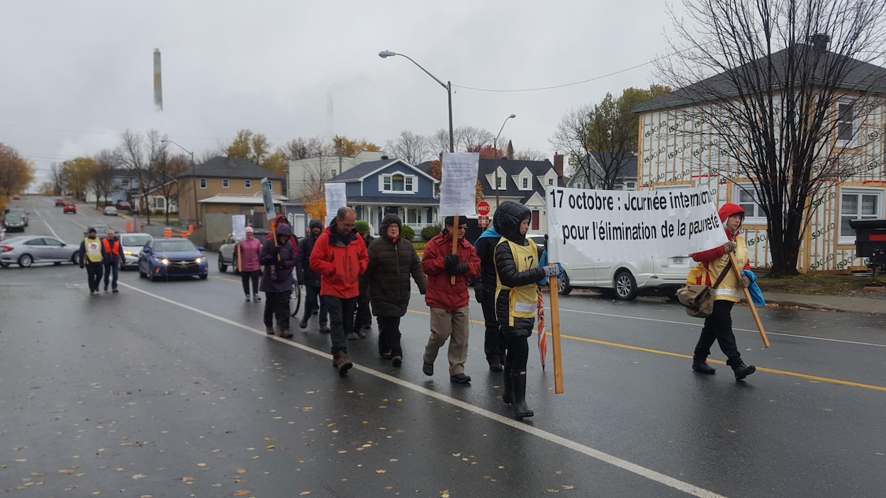 Des personnes marchent dans la rue, les premières tenant une affiche indiquant 17 octobre, Journée internationale pour l'élimination de la pauvreté.