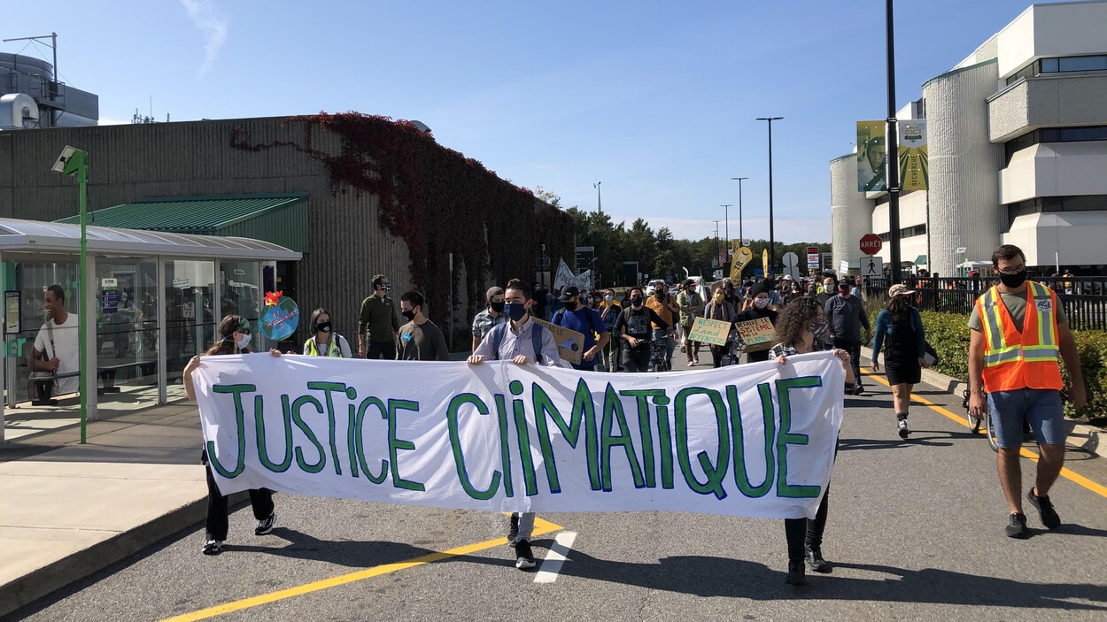Des manifestants tiennent une banderole sur le campus de l'UQTR.