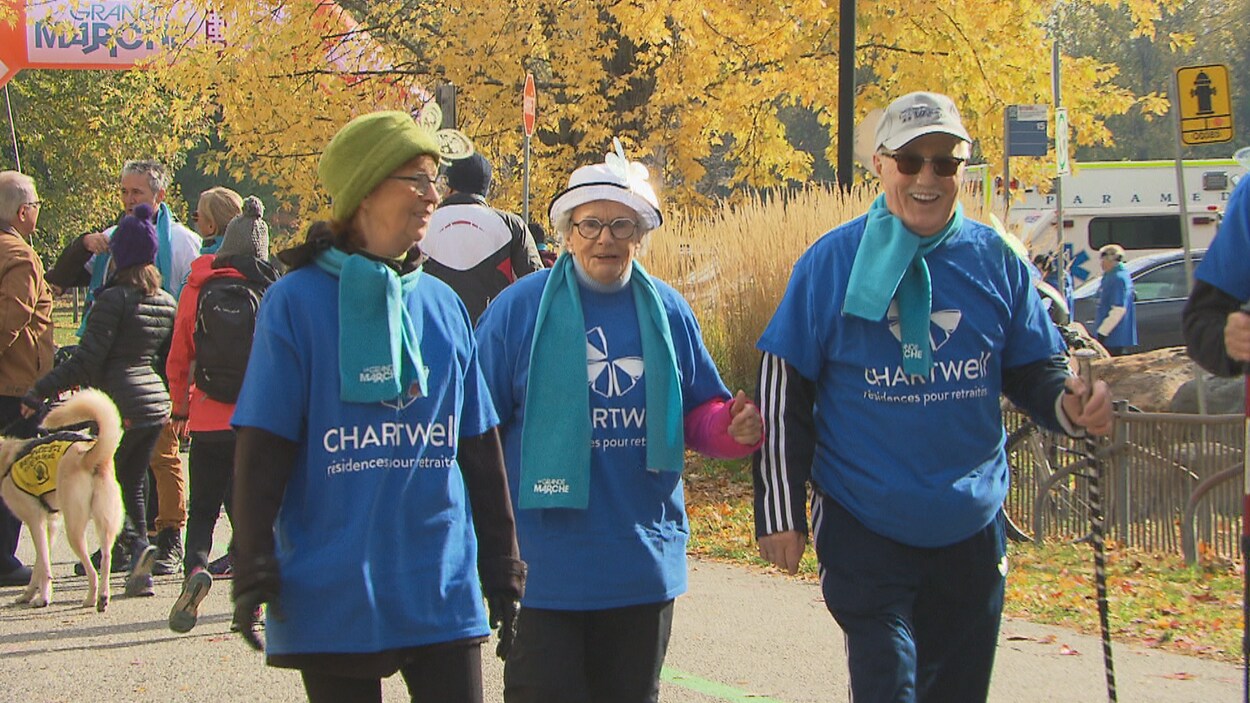 Trois personnes âgées vêtues d'un chandail Chartwell marchent en souriant lors de la marche Pierre Lavoie.