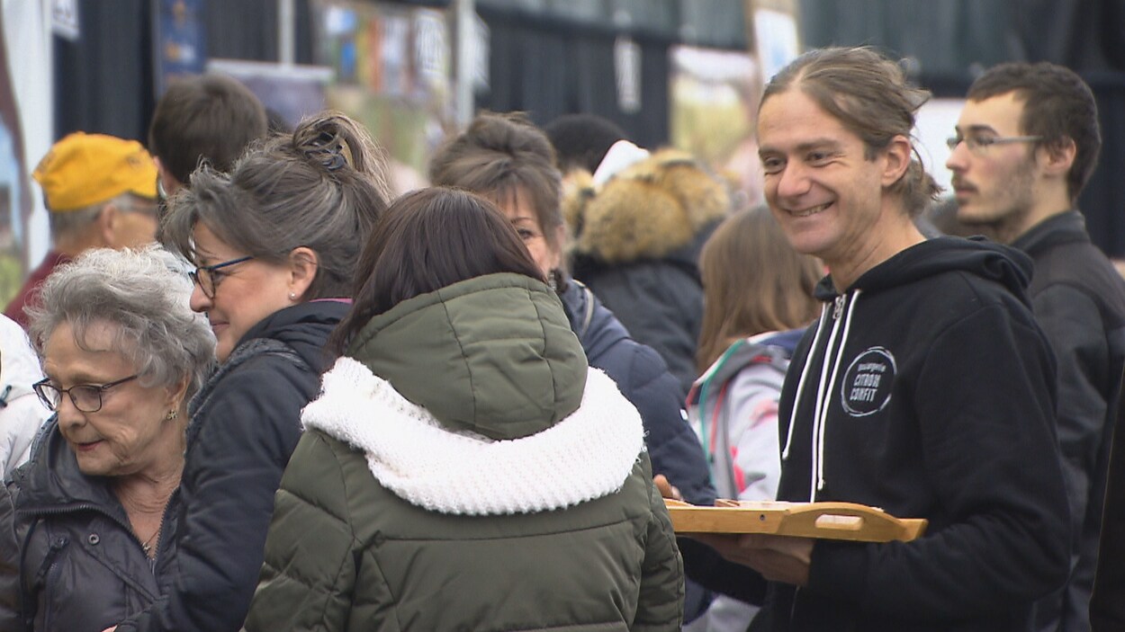 Une foule et un homme sourit à des visiteuses.