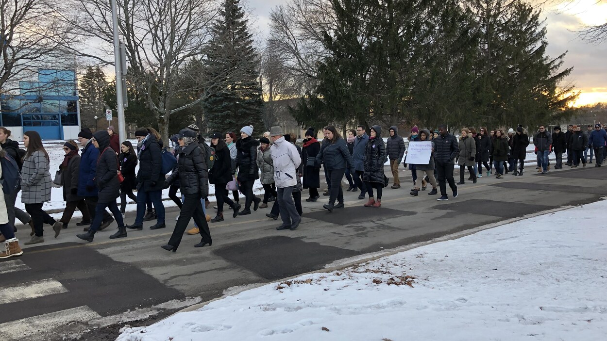 Des étudiants de l'Université de Moncton marchent dehors pour commémorer les femmes tuées en 1989 à Polytechnique.