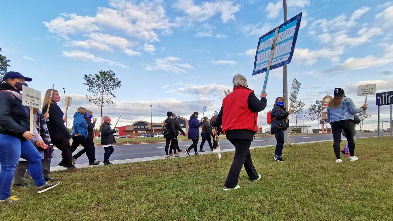 Plusieurs personnes marchent sur le trottoir du boulevard Laure à Sept-Îles.