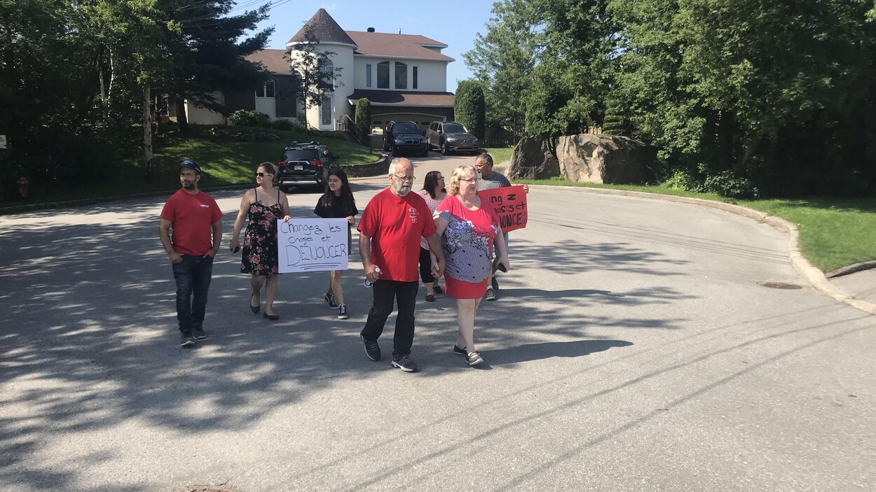 Plusieurs personnes marchent dans la rue, toutes habillées avec un accessoire rouge.