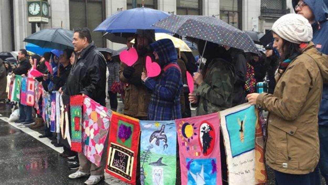 Des dizaines de personnes marchent sous la pluie dans le quartier Downtown Eastside de Vancouver, le 14 février 2016, en hommage aux femmes autochtones disparues ou assassinées. Des dizaines de personnes marchent sous la pluie dans le quartier Downtown Eastside de Vancouver, le 14 février 2016, en hommage aux femmes autochtones disparues ou assassinées.
