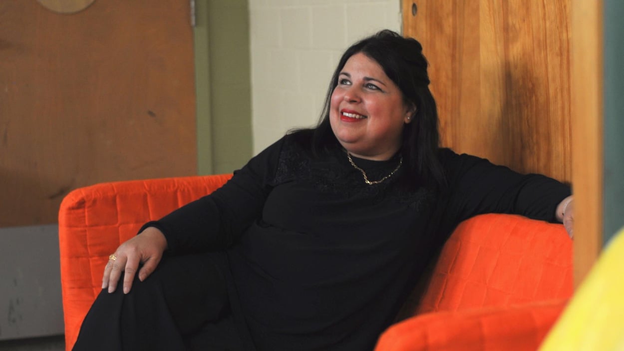 Maria Pullara assise sur un divan orange au centre de sa classe.