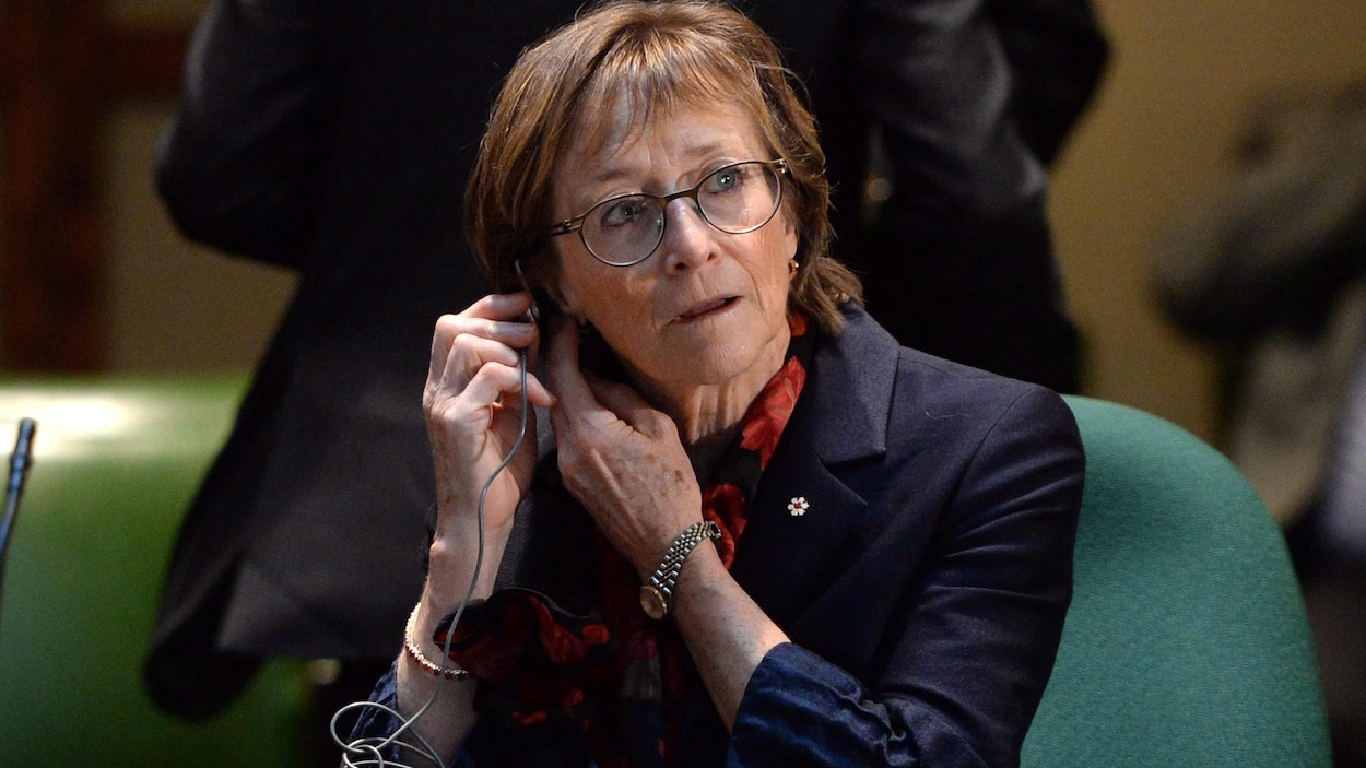 Marie Deschamps place un appareil auditif dans son oreille.