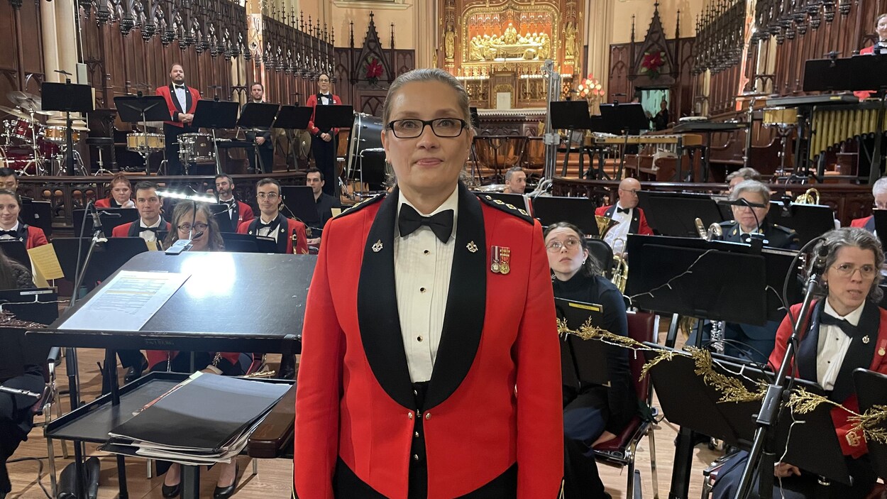 La capitaine Marie-Perle Broadley se tient devant les musiciens sur scène er regarde la caméra.
