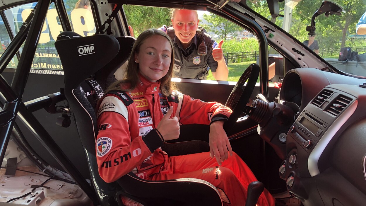 Marie-Soleil Labelle et une agente du Service de police de la Ville de Gatineau posent dans une voiture de course, avec un pouce levé.