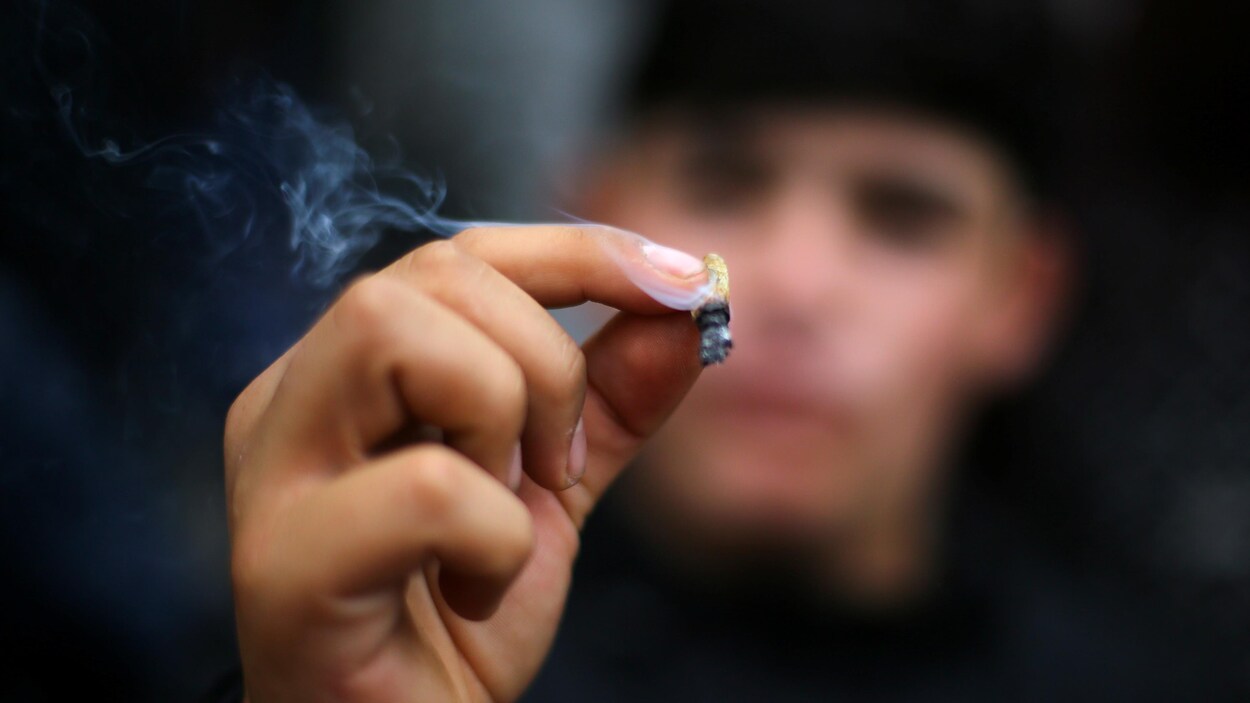 Un homme tient un joint de marijuana. Le monde des affaires réclame des règles claires sur la question en milieu de travail.