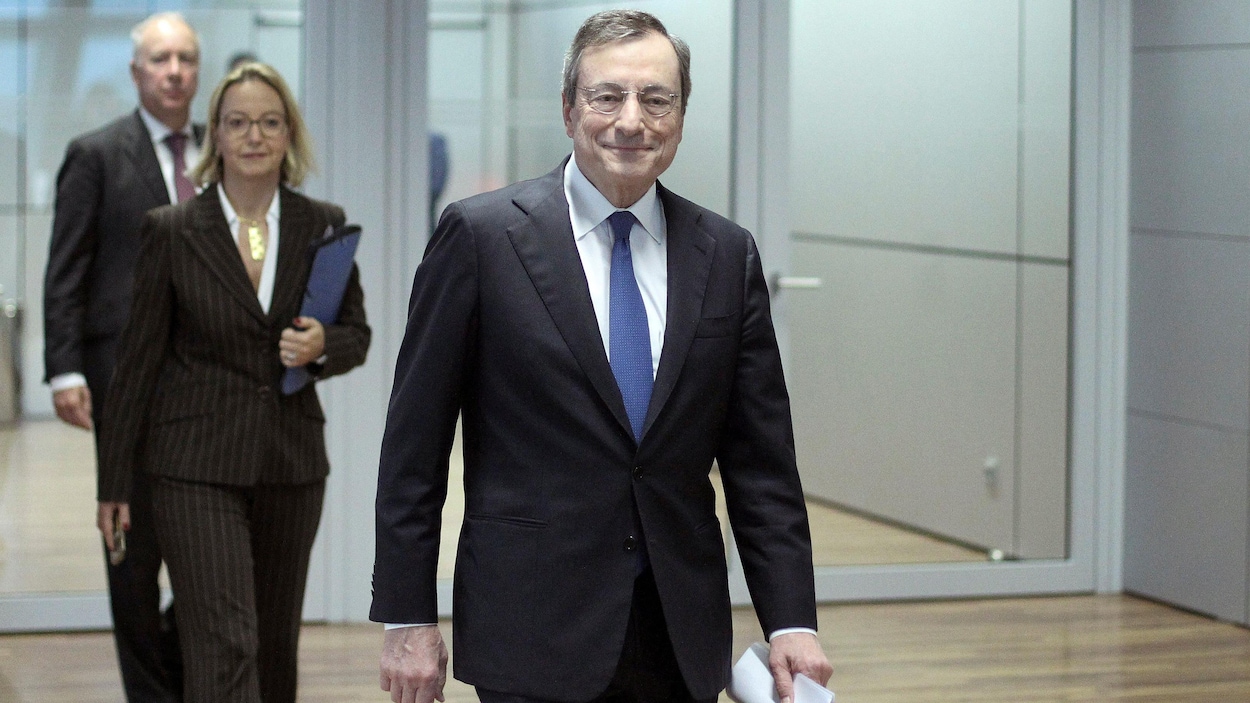 Mario Draghi marche dans un corridor, des feuilles en main.
