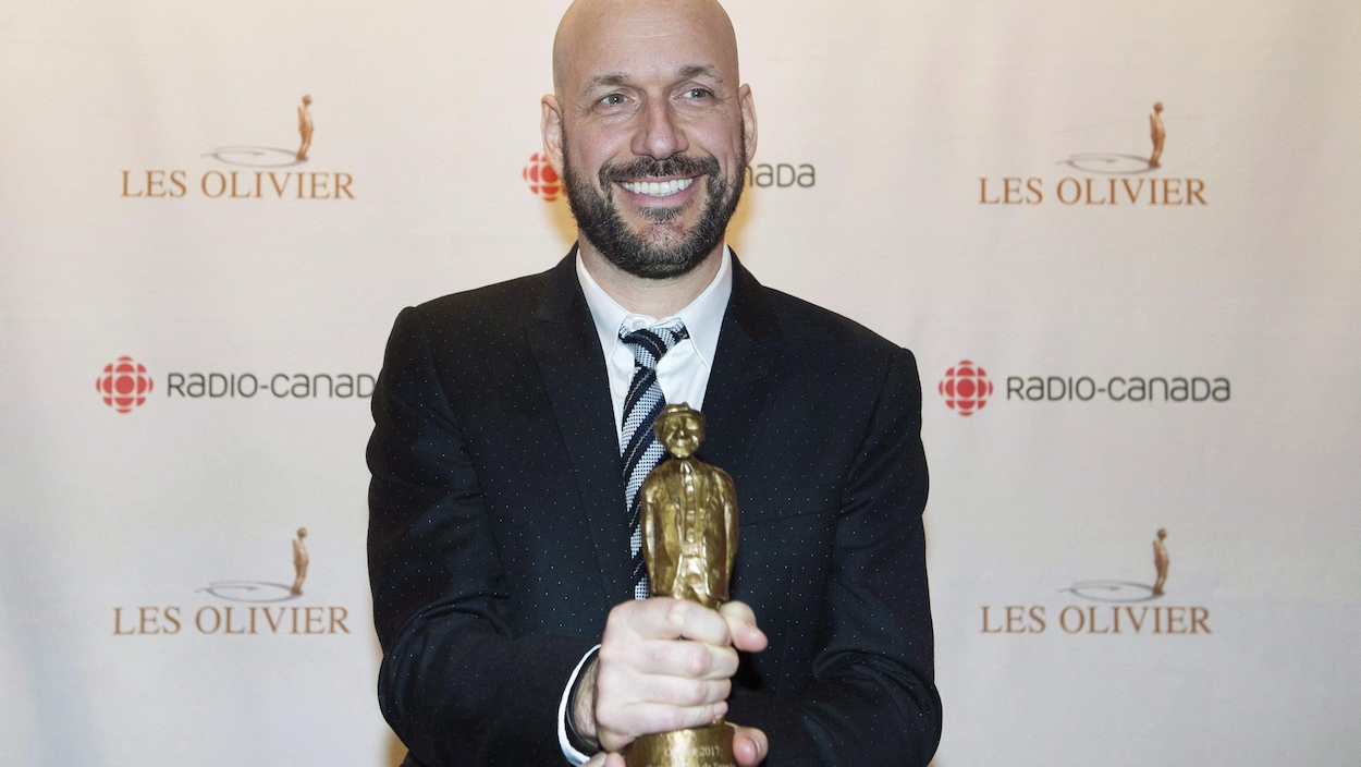 L'homme tient son trophée et sourit.