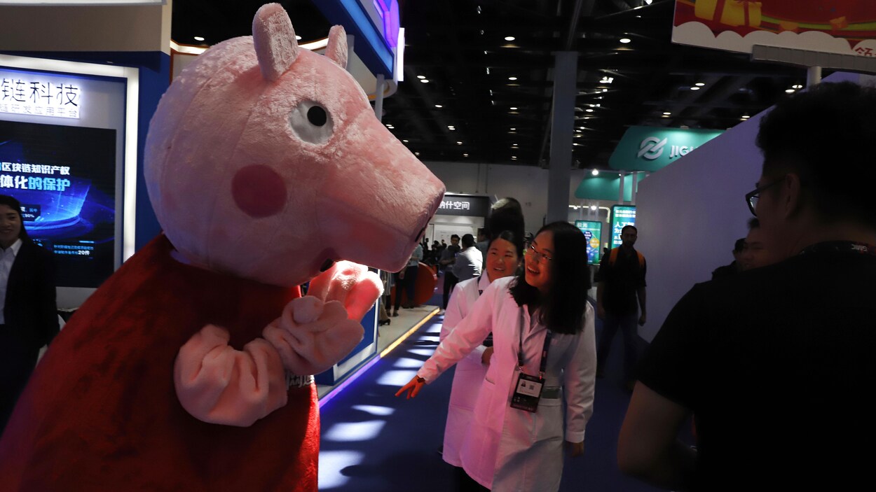 Deux femmes sourient en croisant la mascotte de Peppa Pig.