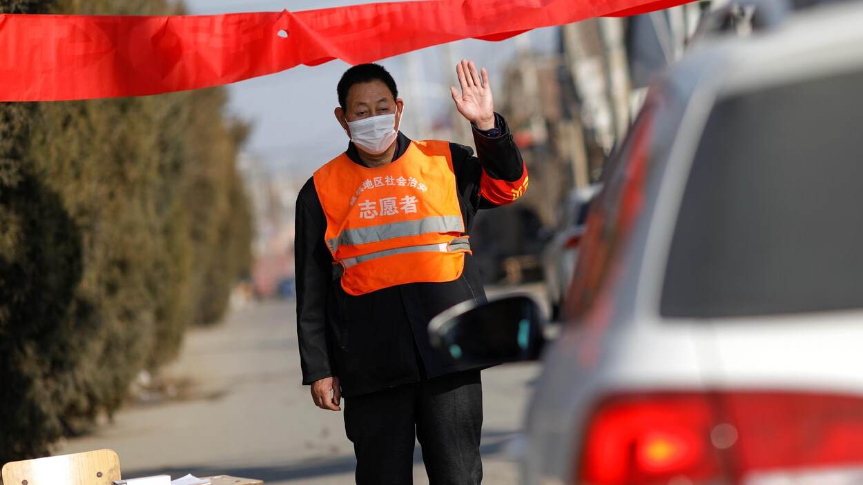 Un homme porte un masque à un barrage routier.