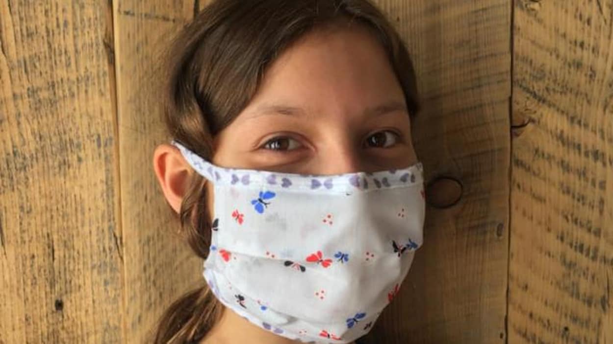 Une jeune fille porte un masque en tissu.
