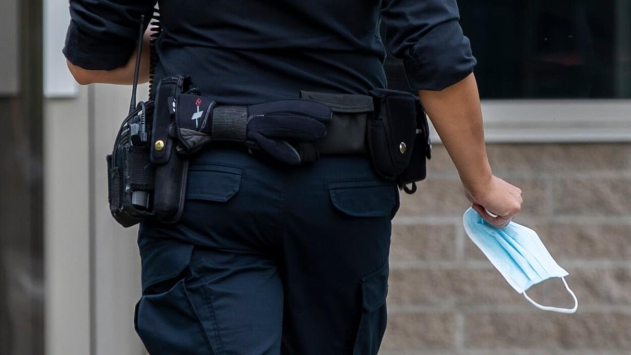 Un policier de dos tient un masque.