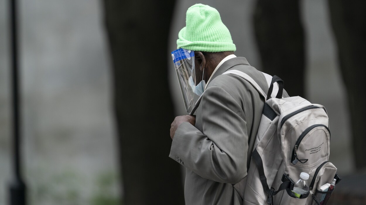 Un homme portant une tuque, un masque, une visière et un sac à dos.