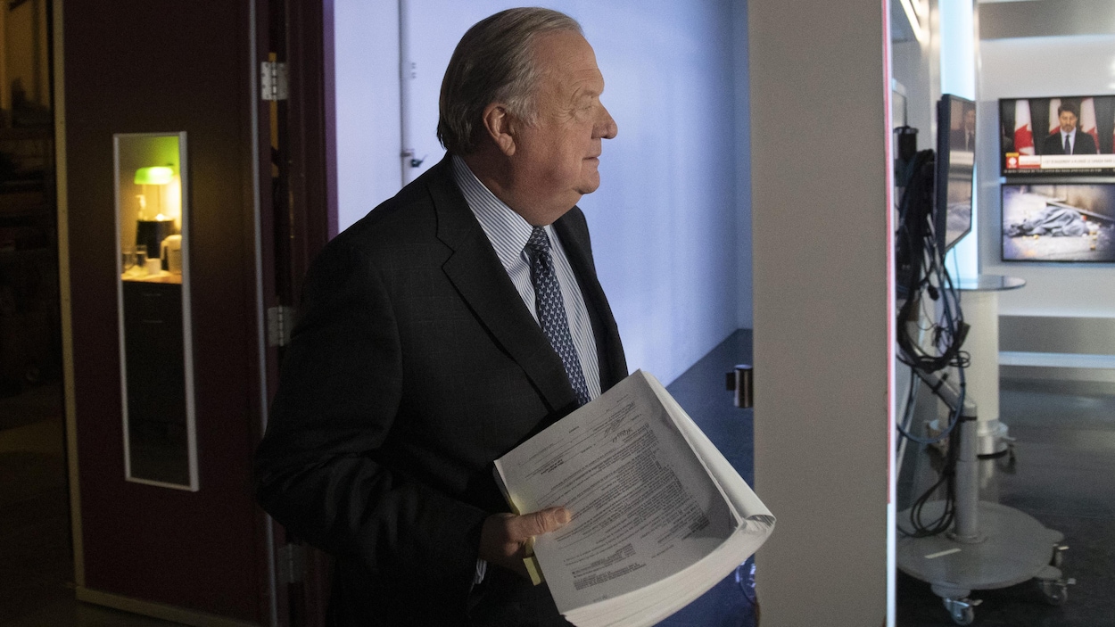 Me Michel Massicotte arrive sur un plateau de télévision avec des documents en main.