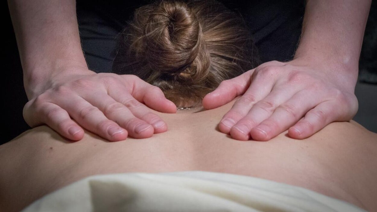 Une femme couchée sur le ventre reçoit un massage thérapeutique sur le dos