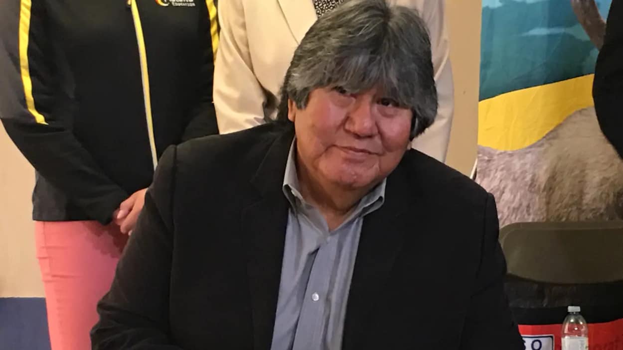 Un homme autochtone en train de signer un document.