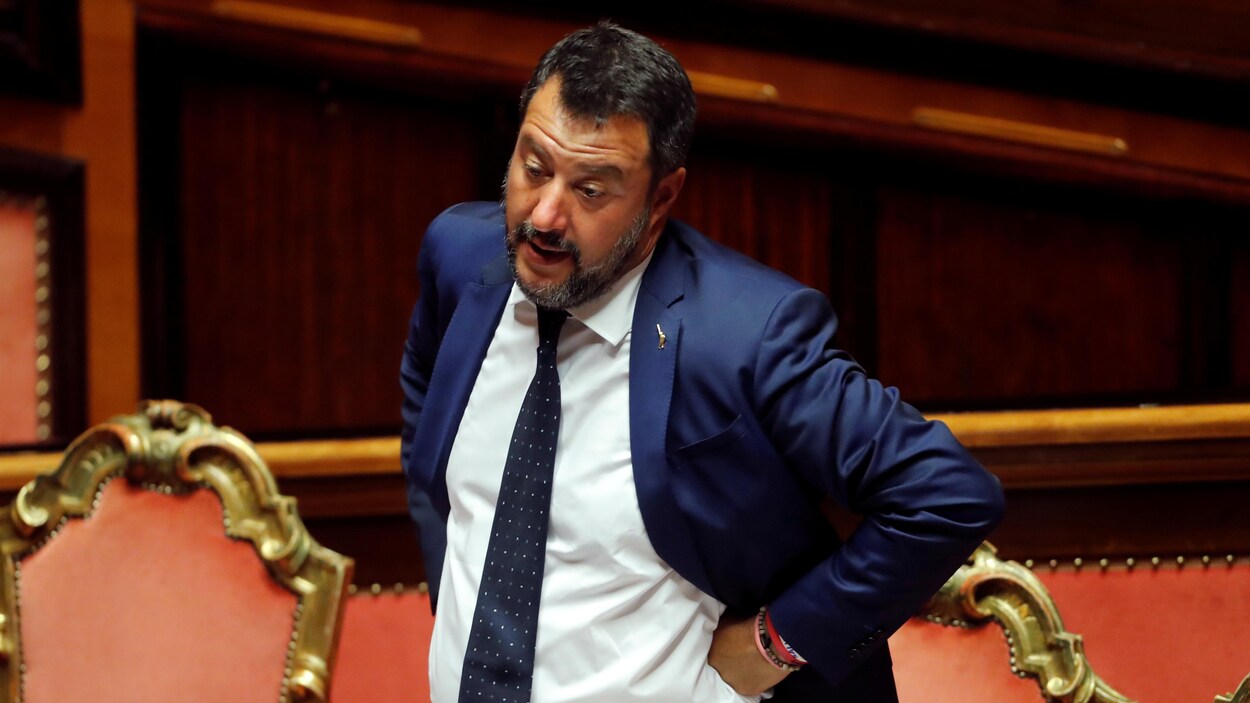 Debout en chambre, Matteo Salvini se dresse les mains sur les hanches.