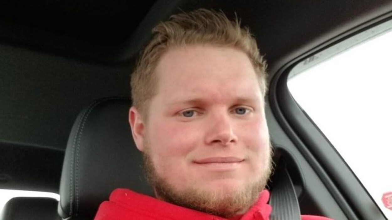 Mathew Ekstrom est assis dans ue voiture. La photo est prise de près. C'est un jeune homme aux yeux bleus avecune barbe et des cheveux blonds.